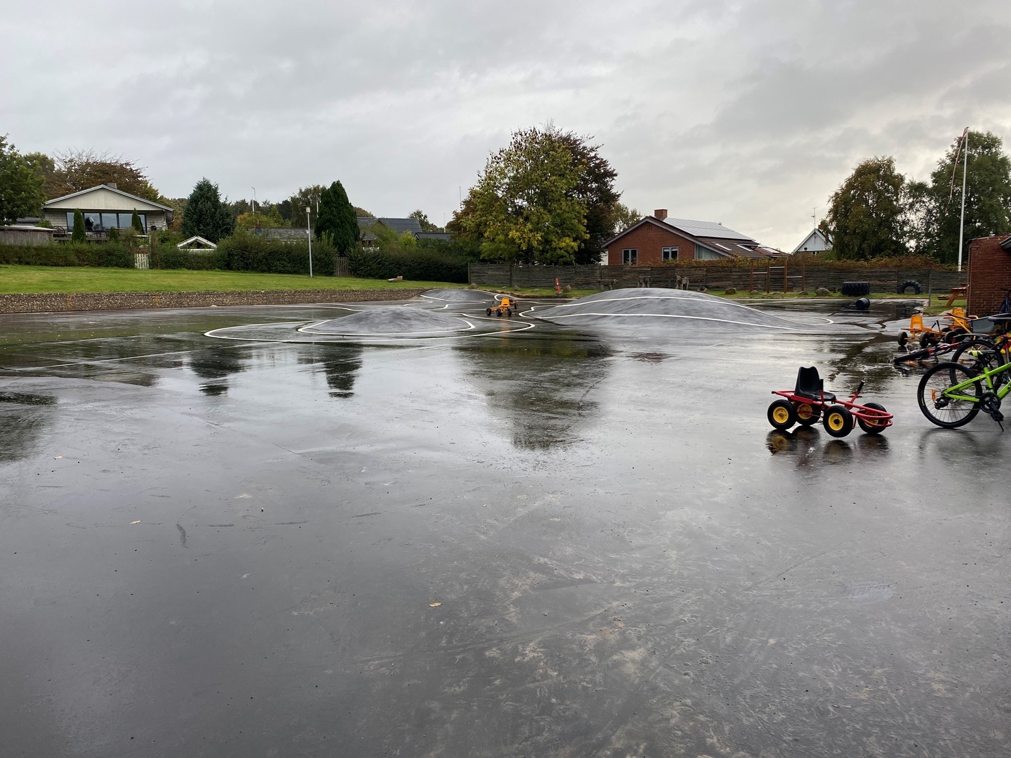 Asfaltplads med optegnet bane, cykler og børnekøretøjer.