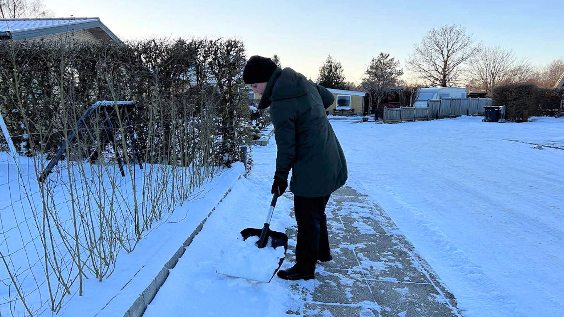Person rydder sne på fortov