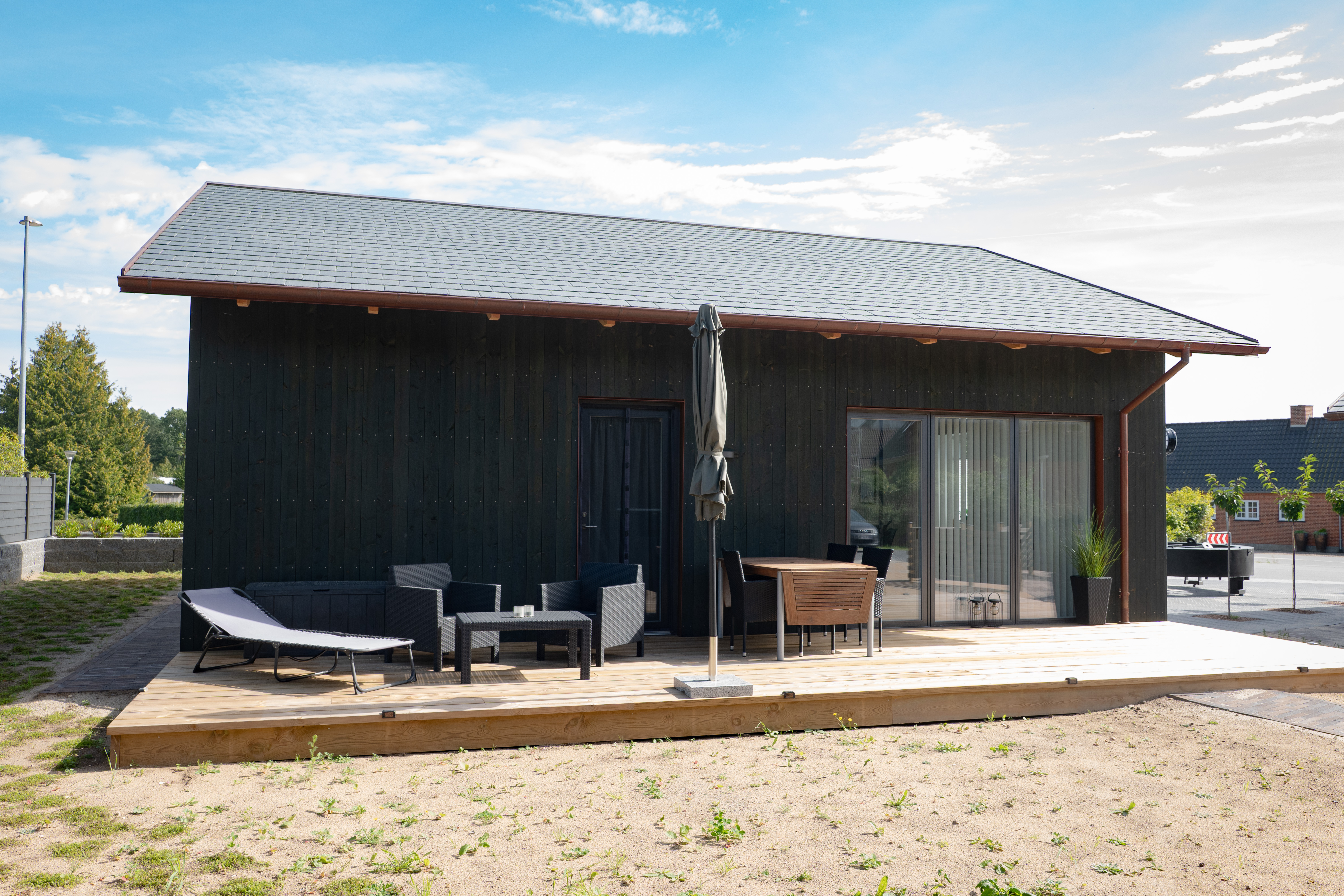 Bygning og træ-terrasse med havemøbler